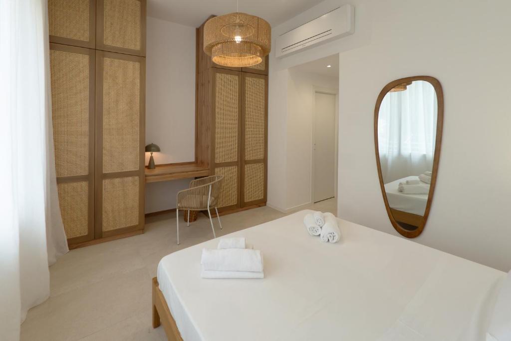 a bedroom with a white bed and a mirror at Cálida apartments in Cefalù