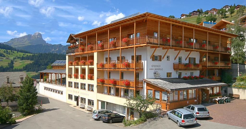 un grande edificio con auto parcheggiate in un parcheggio di Hotel Pider a La Valle