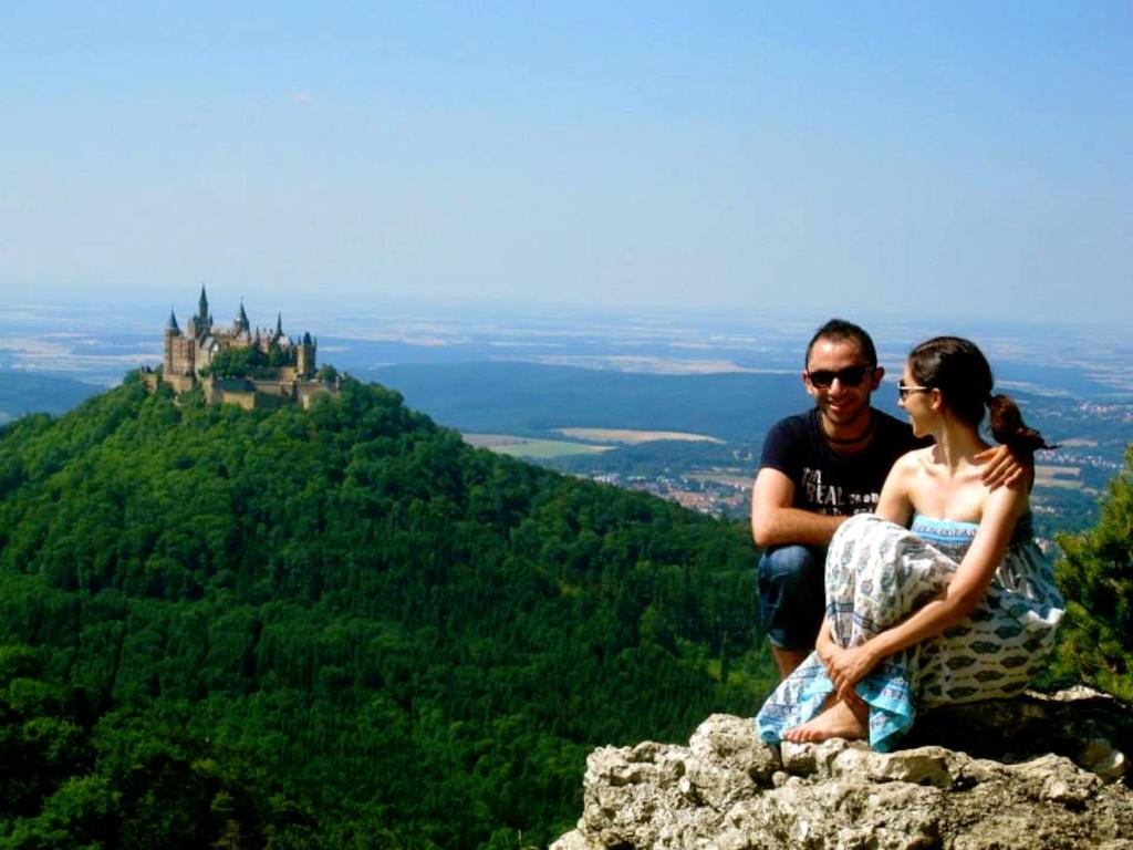 a man and woman sitting on top of a mountain with a castle at Ferienwohnung Am Ziegelbach in Hechingen