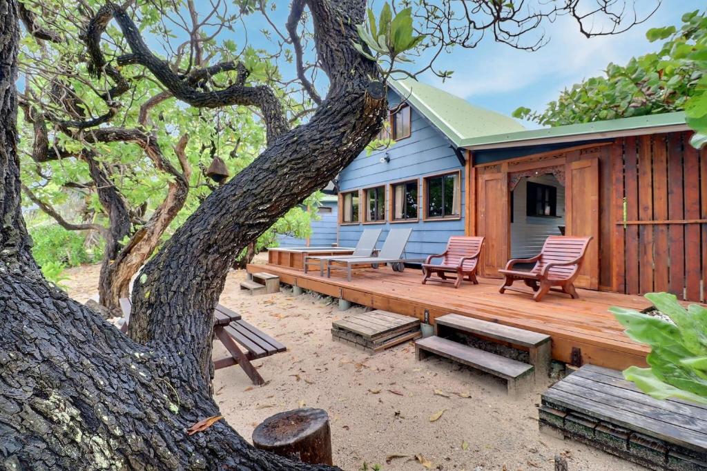 una casa azul con bancos y un árbol en Fare Vainina - Charmante maison de plage près du golf, en Moorea