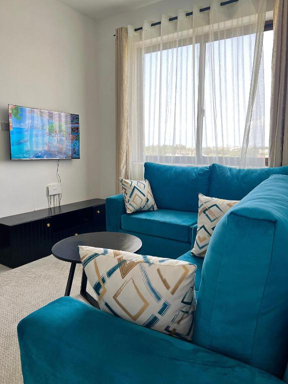 a living room with a blue couch and a table at Saka Homes, Cozy 1-BR Bamburi in Mombasa