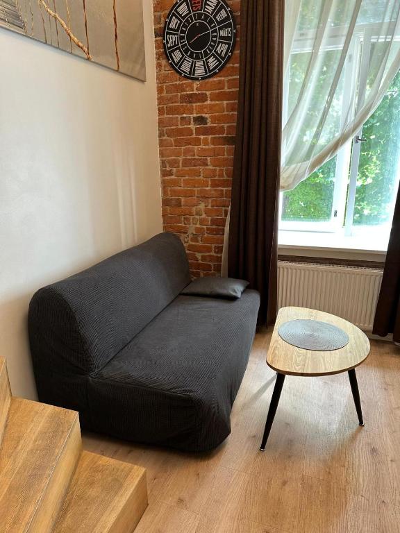a black couch in a living room with a clock at Small Cozy two-level Apartments 9 in Tallinn