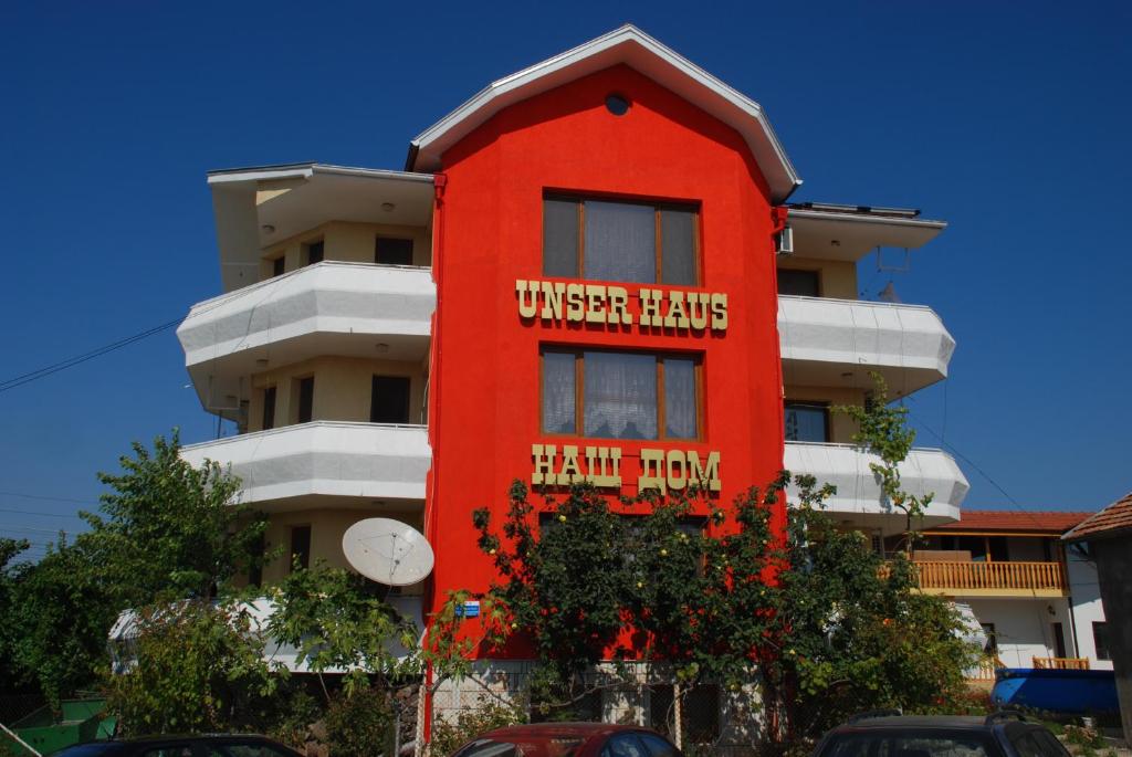 un edificio rojo con las palabras que Harry conoce en él en Guest House Nash Dom, en Kavarna