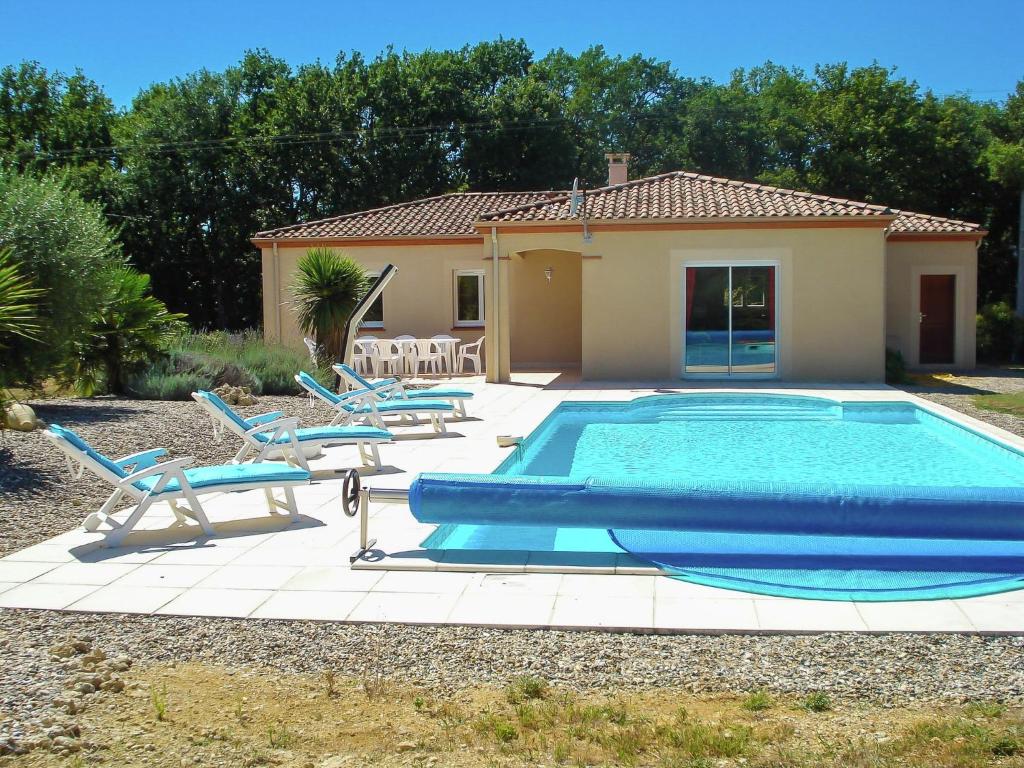 a swimming pool with two blue chairs and a house at Panoramic Poolside Villa in La Croix-Blanche
