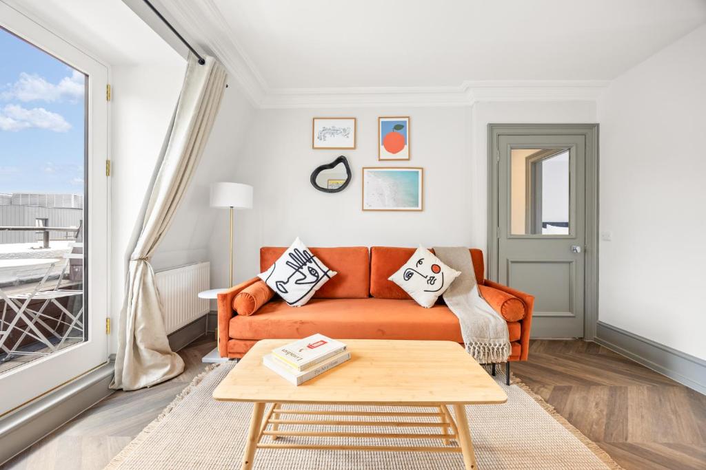 a living room with an orange couch and a table at Stay Kula London - Covent Garden Maiden Lane in London