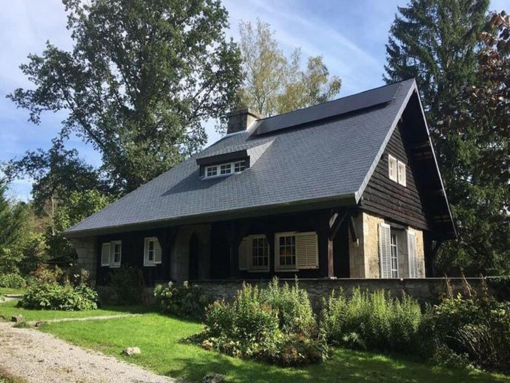 a house with a black roof on a yard at Large hunting lodge with enormous beautiful garden in Vielsalm