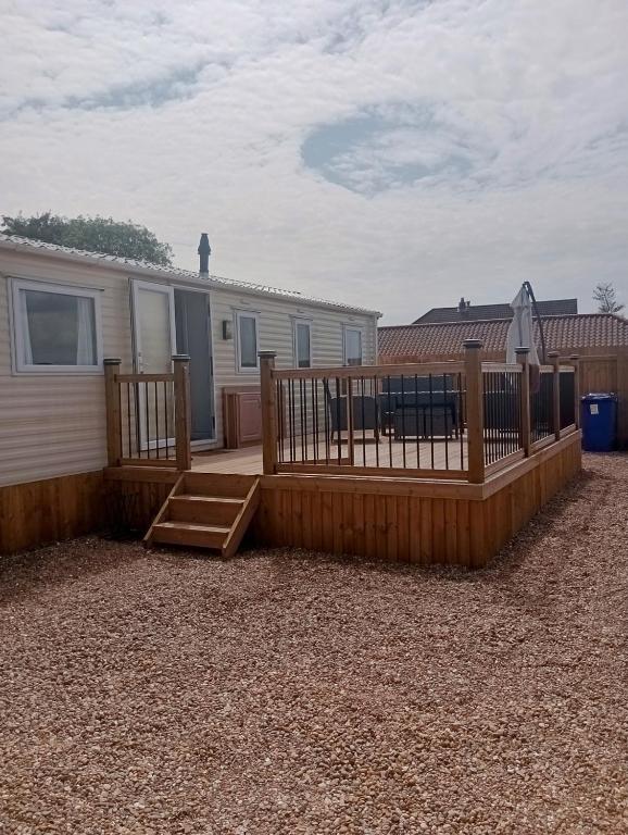 a house with a wooden deck and a fence at Lapwing Lodge, Howdales in Louth