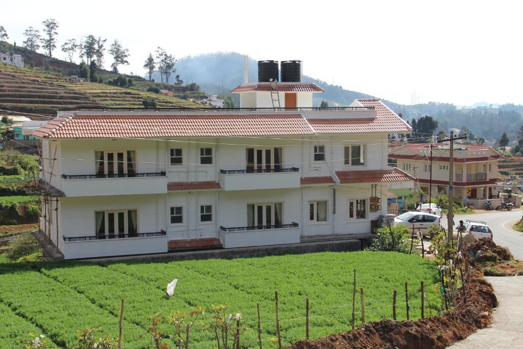 a large white house with a green field in front of it at Golden Springs in Ooty