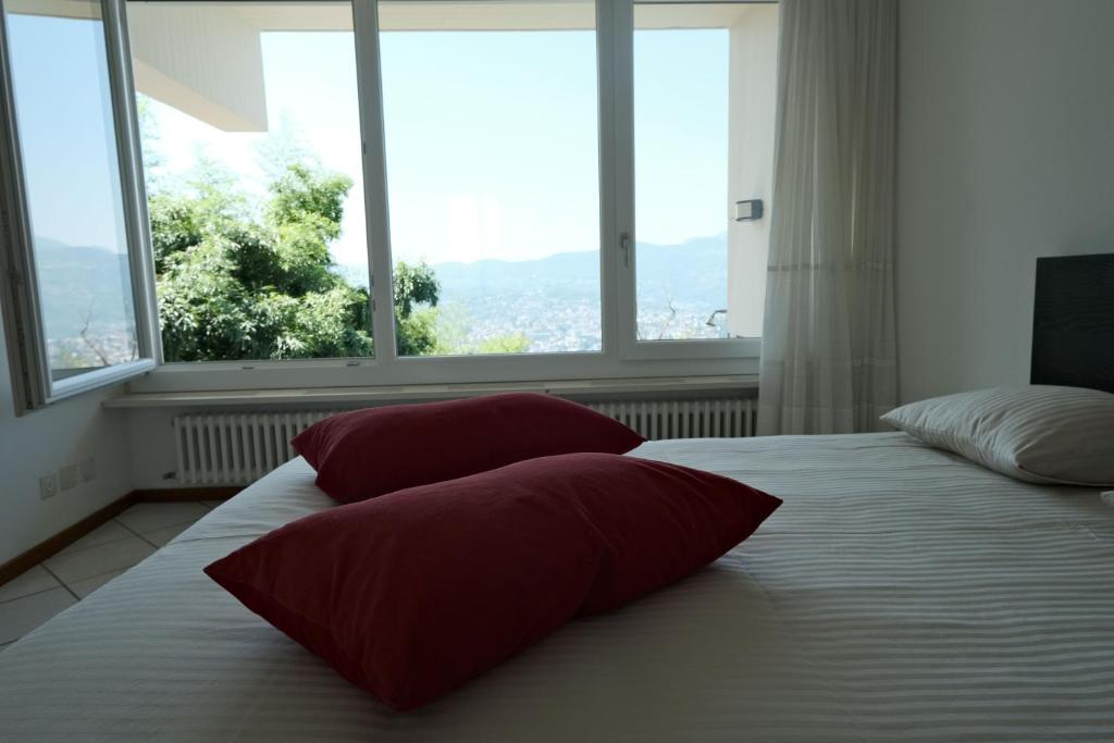 a bedroom with two pillows on a bed with windows at Casa-Cleo in Lugano