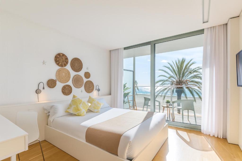 a white bedroom with a bed and a balcony at Meraki Beach Hotel - Only Adults in Playa Pobla de Farnals