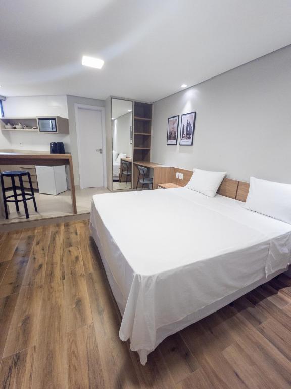 a bedroom with a large white bed in a room at HG Studio Hotel in Governador Valadares