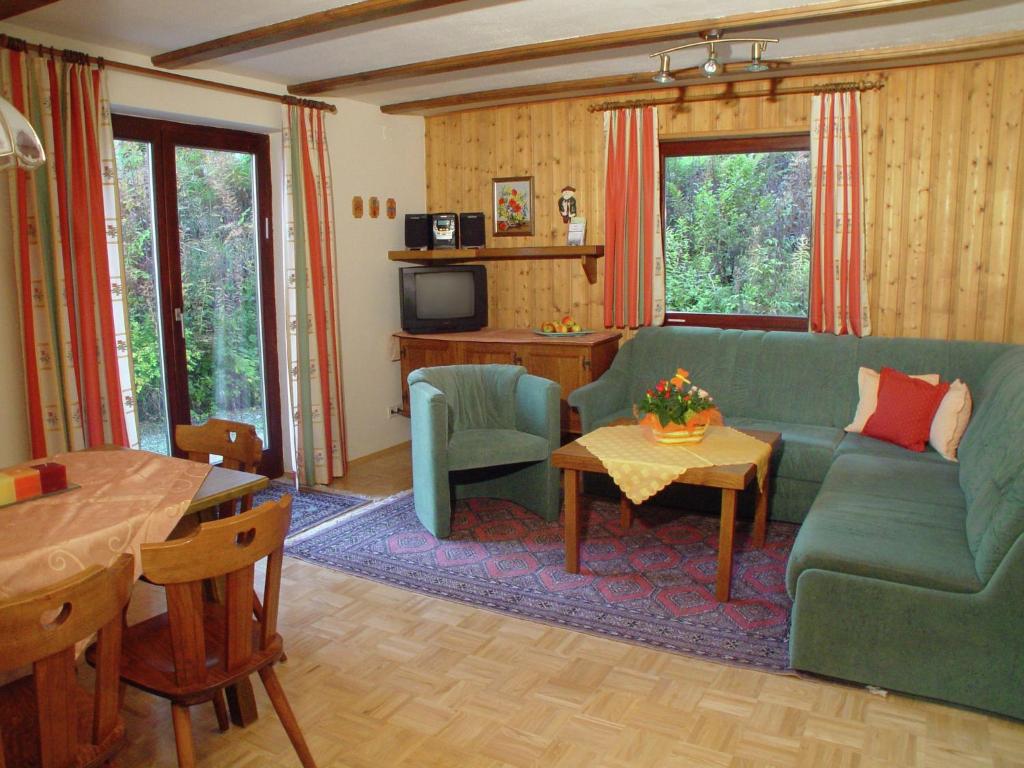 Una sala de estar con un sofá verde y una mesa. en Apartment Nassfeld near Ski Slopes, en Sonnenalpe Nassfeld