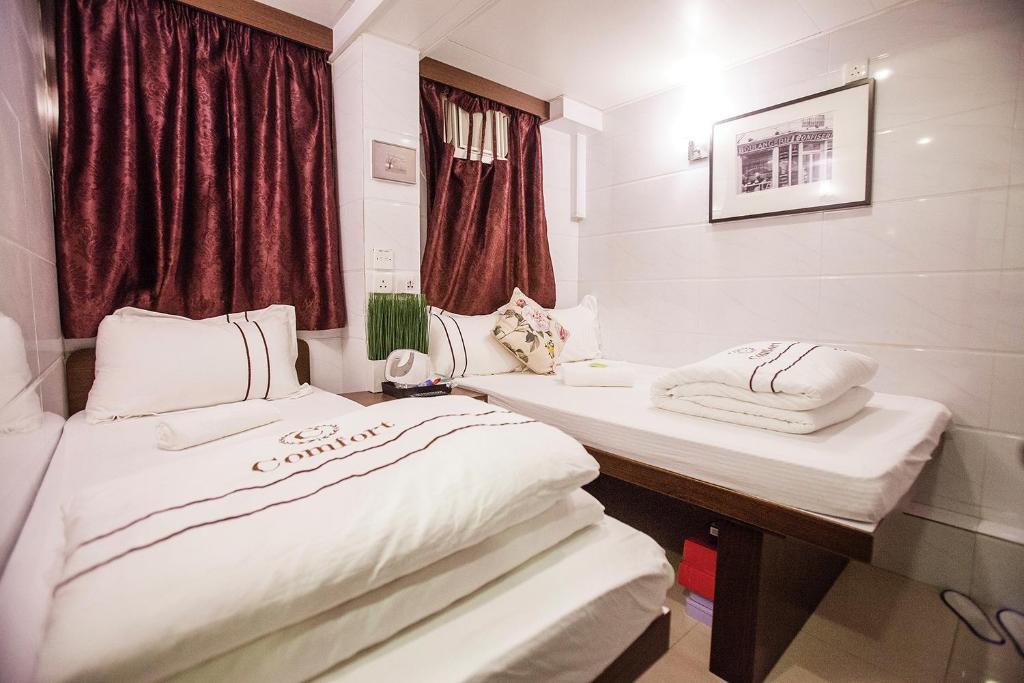 2 camas en una habitación de hospital con ventana en Sun Guest House en Hong Kong