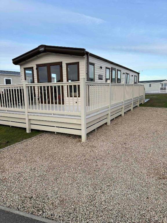 a white mobile home with a white fence at Jen's Retreat in Lossiemouth