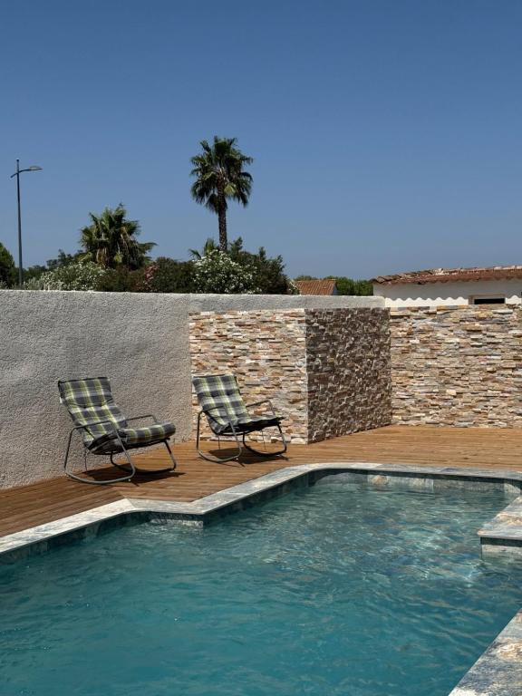 two chairs sitting next to a swimming pool at Villa avec piscine privée entre terre, ville et mer in Sauvian