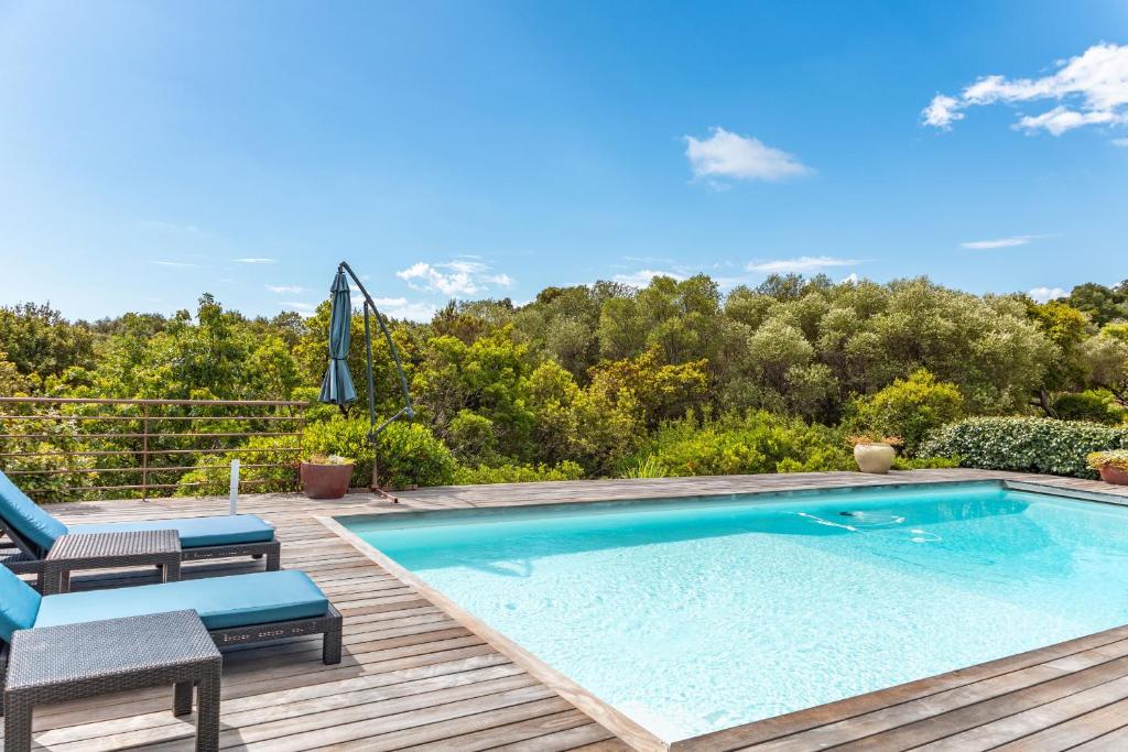 una piscina en una terraza con 2 sillas y una sombrilla en Villa Pina, en Sainte-Lucie de Porto-Vecchio