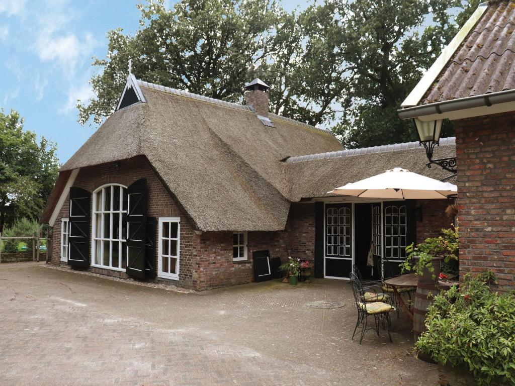 a brick house with a roof with a table and an umbrella at Villa in Ommen with Private Pond in Rheezerveen