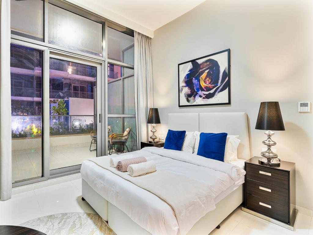 una camera da letto con un letto grande e una grande finestra di Savis Homes - Furnished Spacious Studio in Golf Promenade 2A by Damac Hills a Dubai