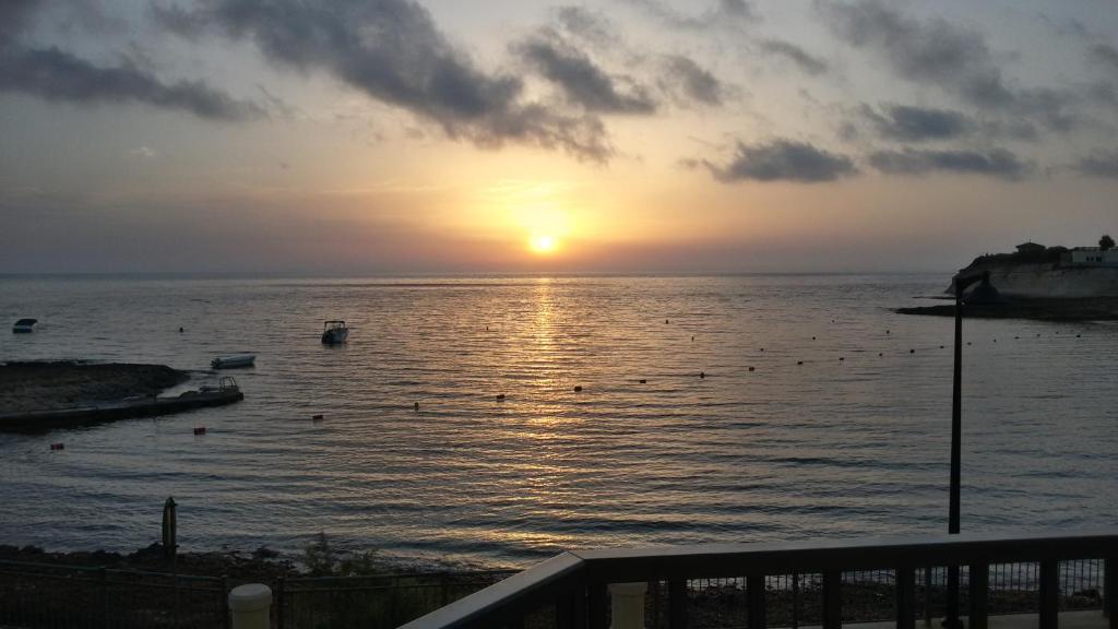 una puesta de sol sobre un cuerpo de agua con gente nadando en Merhba APT 3, en Marsalforn