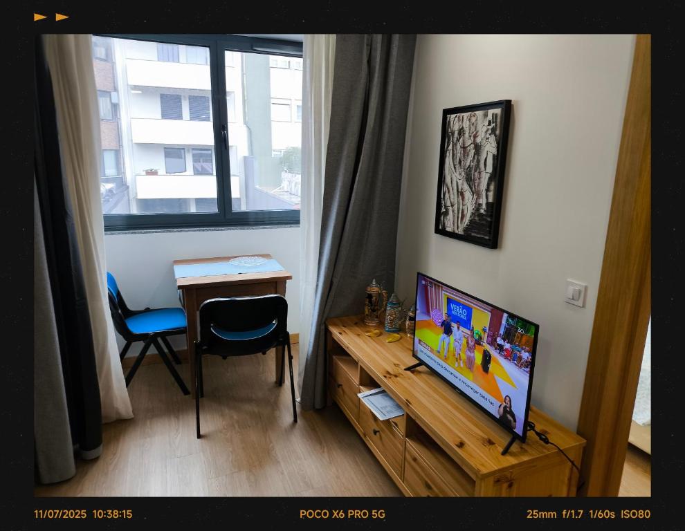 Una habitación con un televisor, una mesa y una ventana. en Porto Stayfleeting 2, en Oporto