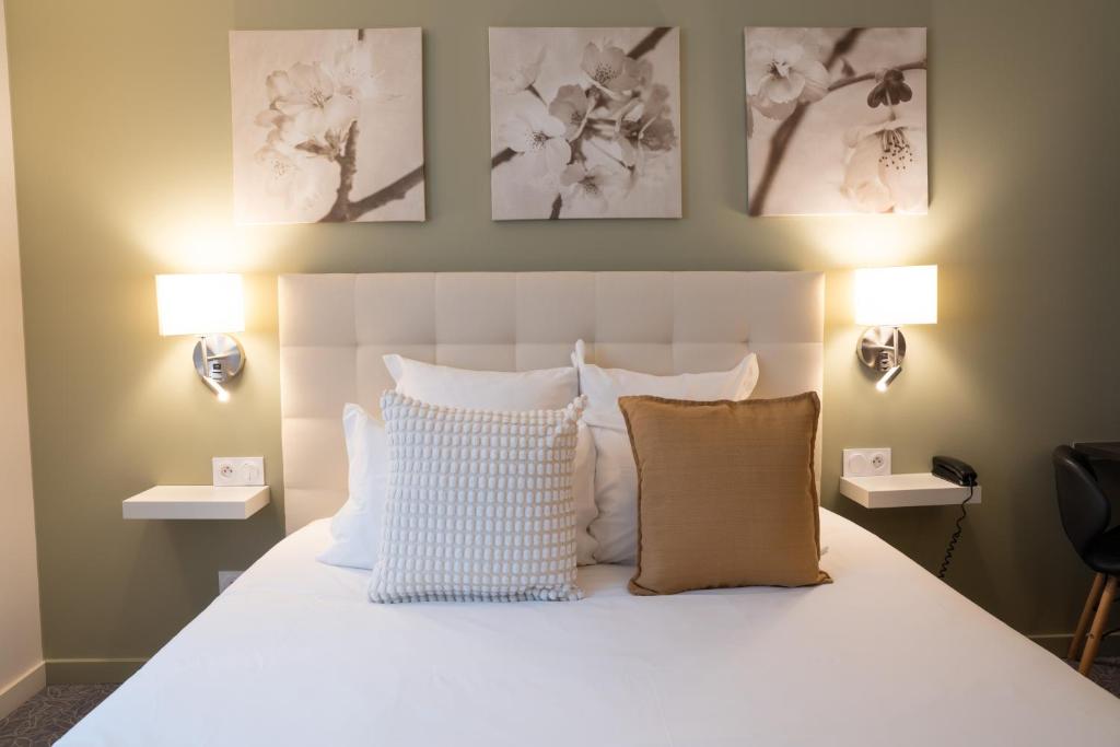 a bedroom with a white bed with pillows and two lights at Hôtel restaurant Vertfeuille in Arc-et-Senans