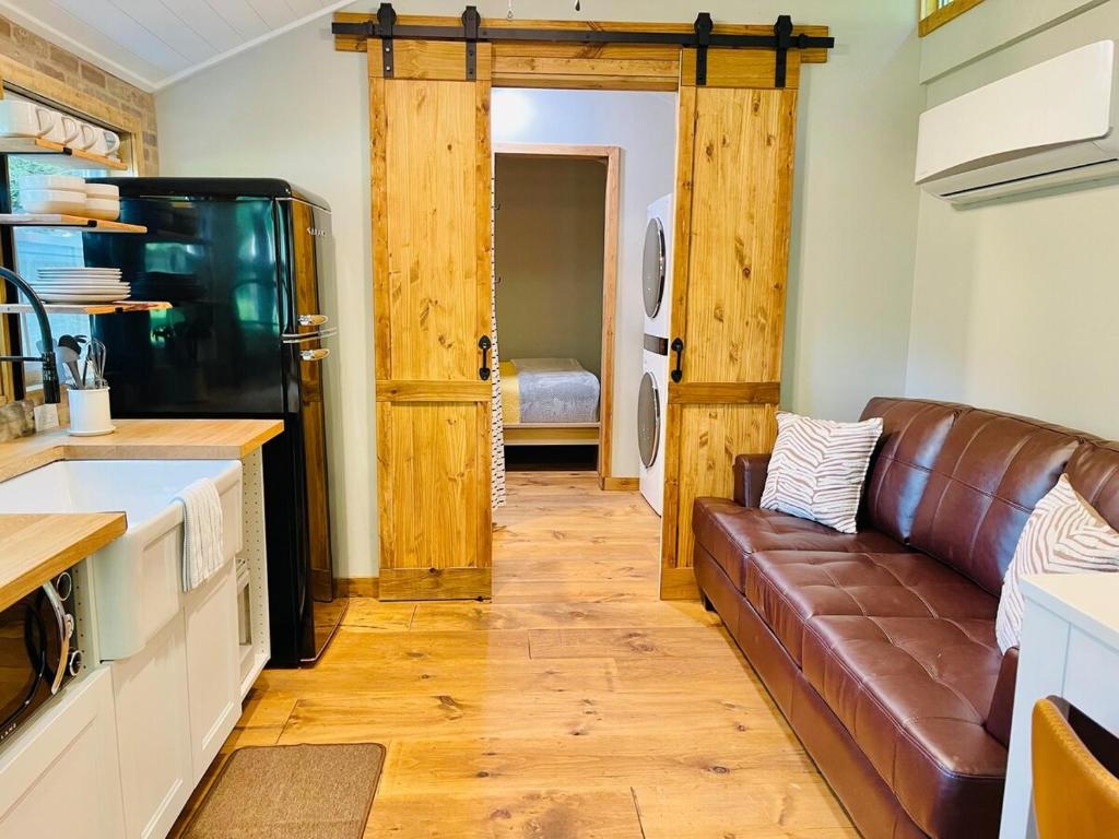 a living room with a brown couch in a kitchen at Jai Hollow Tiny Home Cottage in Robbinsville