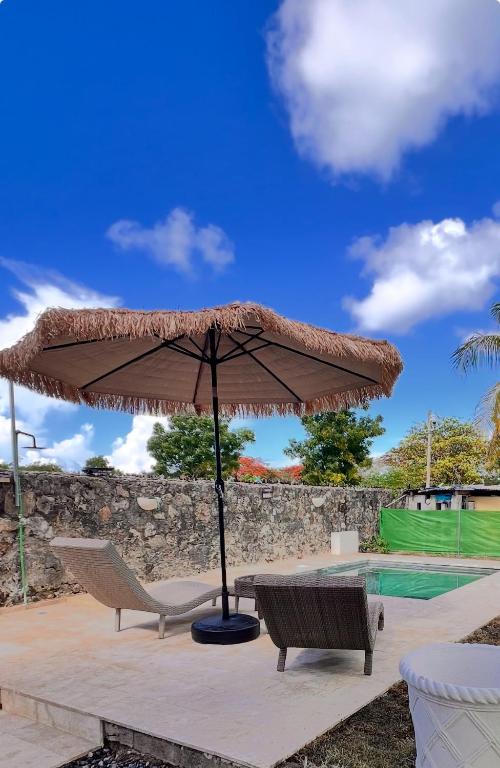 a patio with an umbrella and chairs and a pool at Residencia Bambou HAVRE DE PAIX in Juan Dolio