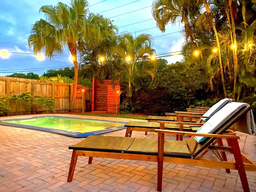 Un grupo de sillas junto a una piscina. en Fox Island Heated Spa- Downtown & Beach, en Fort Lauderdale