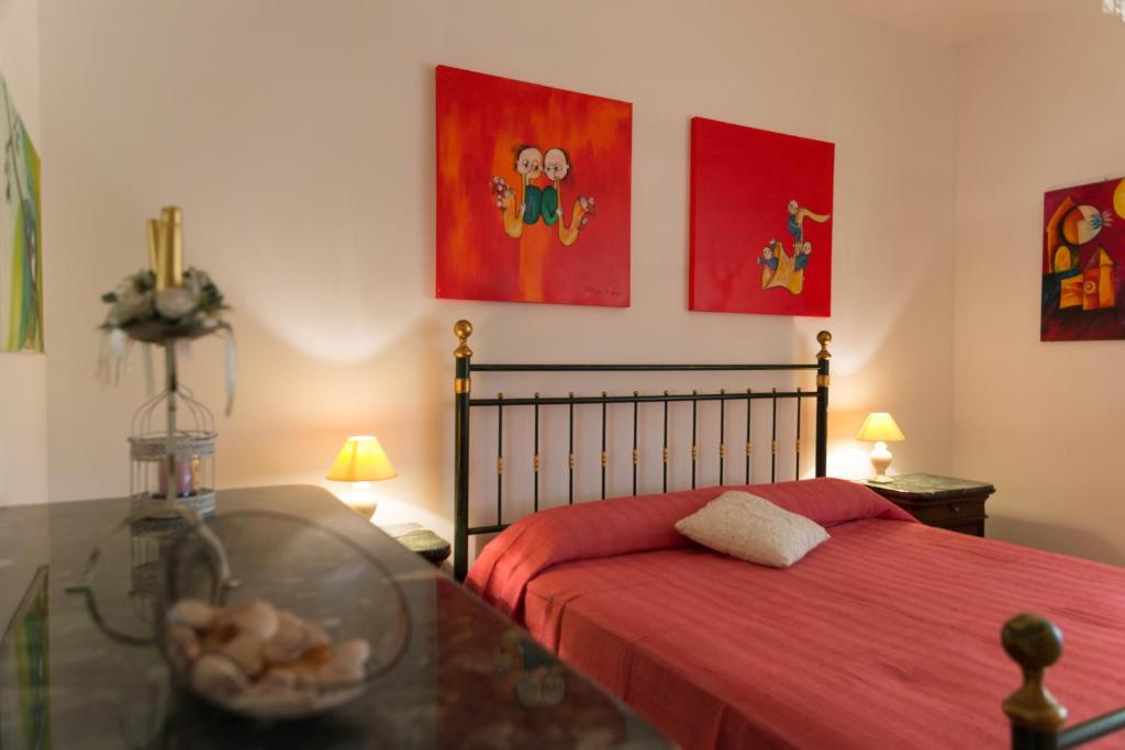 - une chambre dotée d'un lit avec des draps rouges et des peintures dans l'établissement Sa Mama e Su Sole, à Alghero