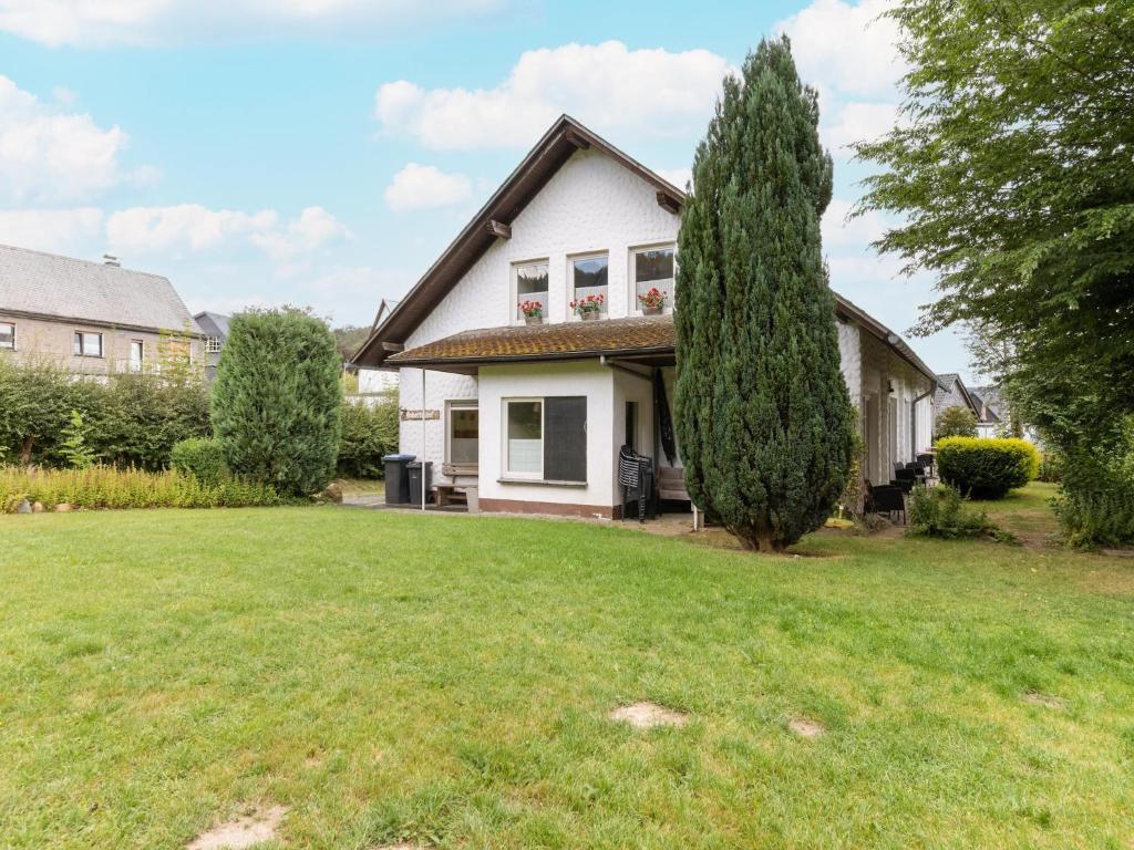 a white house with a tree in the yard at Ferienwohnung in der Nähe von Skipisten in Winterberg