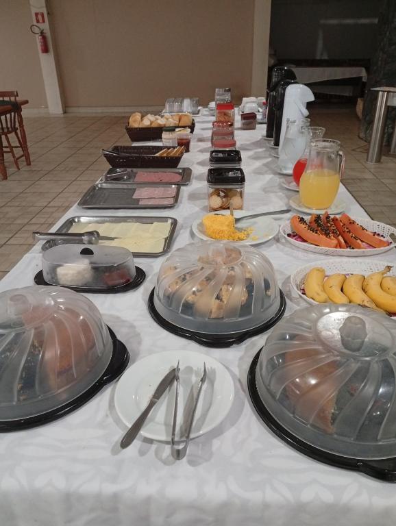 a long table with plates of food on it at Hotel Castro Alves Norte in Marília