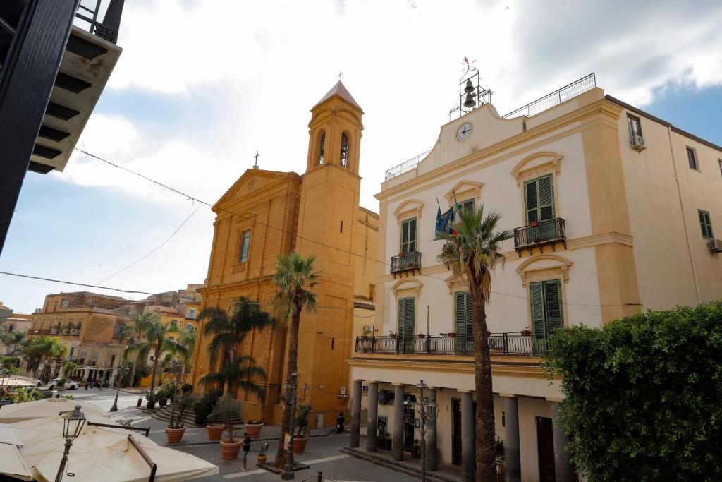 a tall building with a clock tower and palm trees at Villa Azzurra Apartment Camilleri's Roads in Porto Empedocle