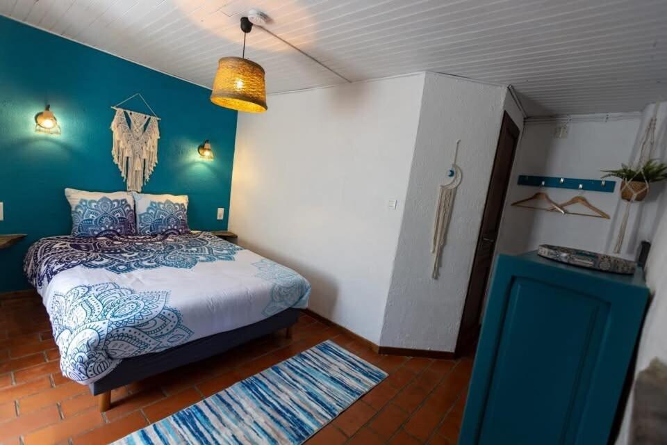 a bedroom with a bed and a blue wall at Les hôtes du châtaignier in Pénens