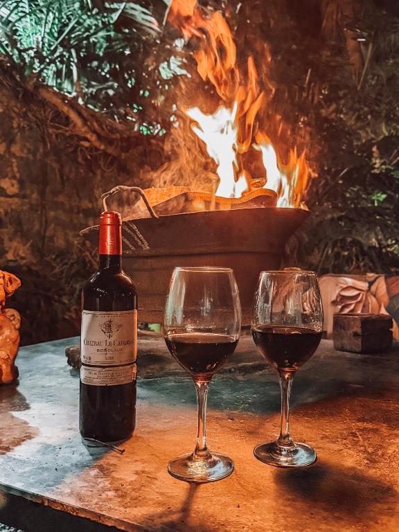 two glasses of red wine next to a fire pit at Pousada Acalanto in São Roque