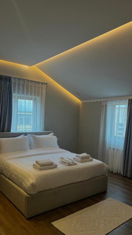 a bedroom with a large white bed with windows at Vila 1940 in Ersekë