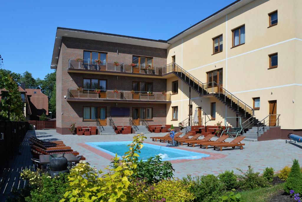 an apartment building with a swimming pool and chairs at Ievų vila in Palanga
