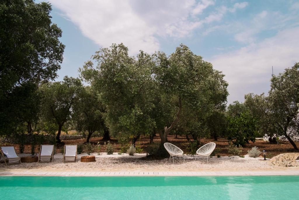 duas cadeiras e uma piscina em frente às árvores em Fikus - the Apulian B&B em Ceglie Messapica