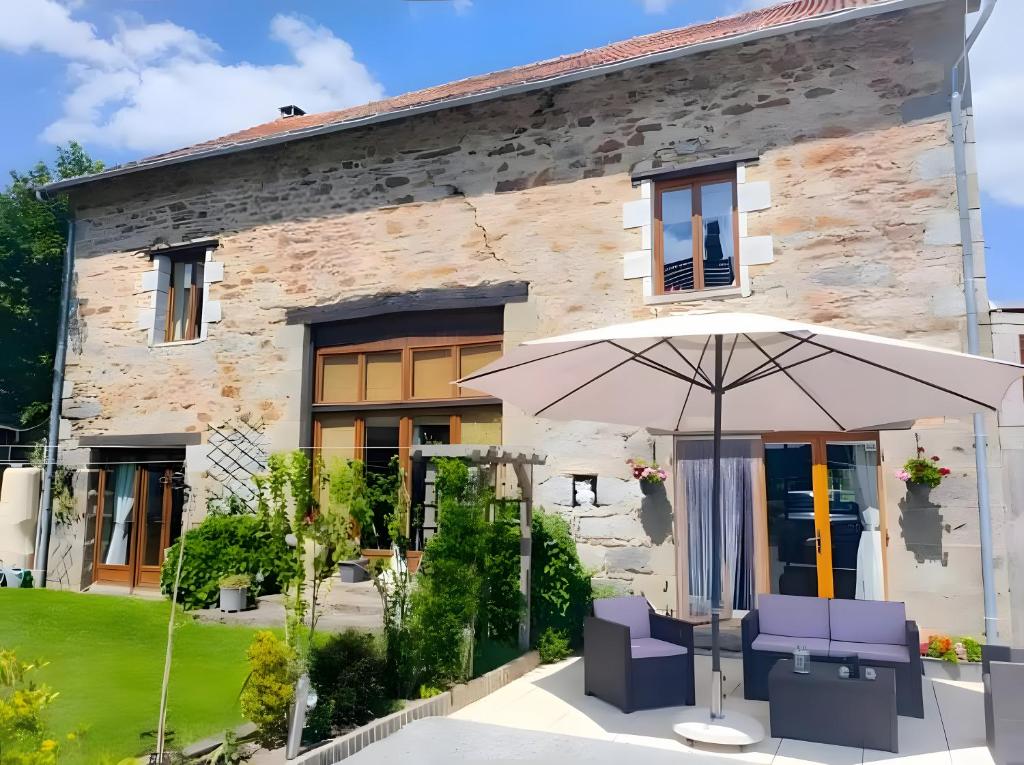 a house with an umbrella in front of it at La Grande Maison de Janaillat in Janaillat