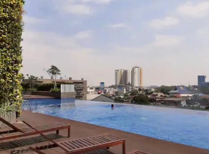ein großes Schwimmbad mit einer Stadt im Hintergrund in der Unterkunft Studio Apartment Springwood By LyaRoom in Warungmangga