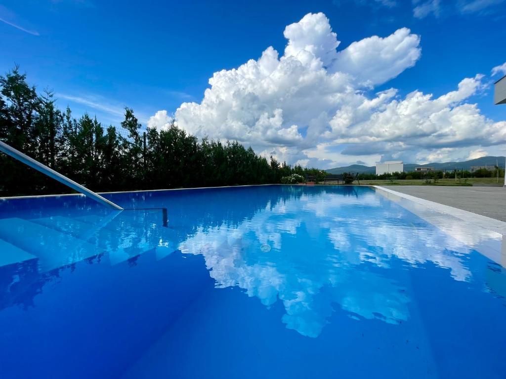 a swimming pool with a blue sky and clouds at DREAM VIEW Saguramo in Saguramo