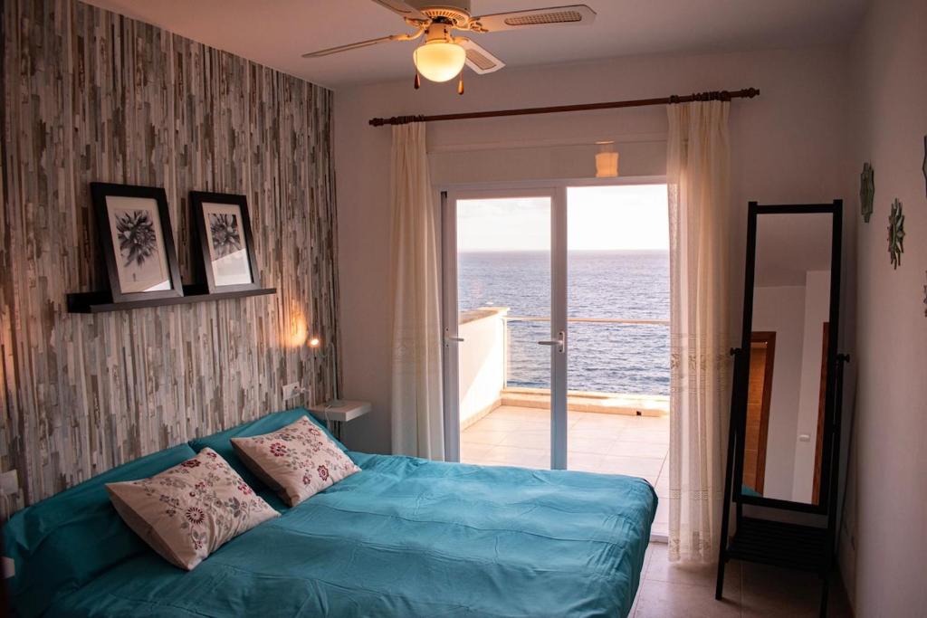 a living room with a blue couch and a view of the ocean at Cas Forner in Cala Pi