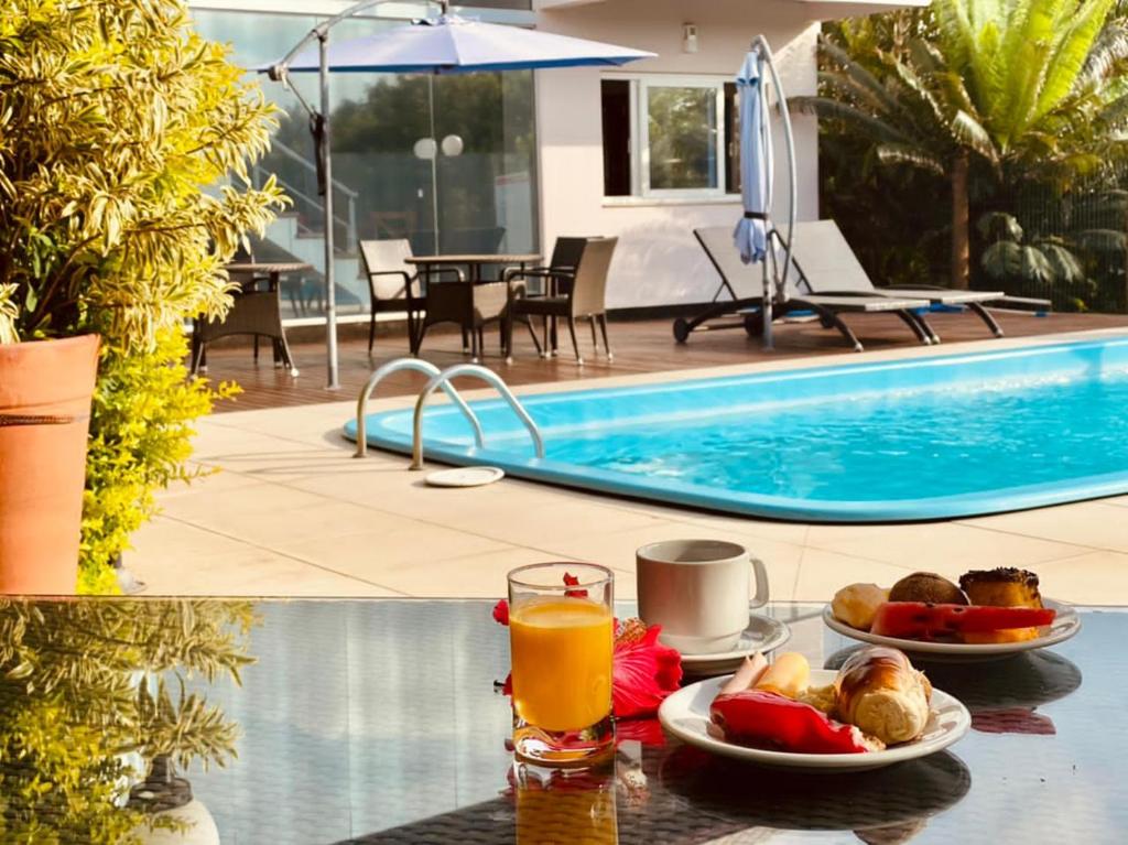 a table with a plate of food next to a swimming pool at Pousada Ilha Faceira in Florianópolis