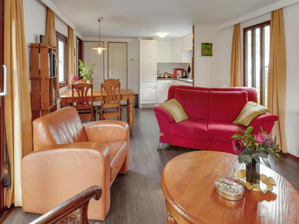 a living room with a red couch and a table at Chalet in Stegeren with Pool and Gardens in Stegeren