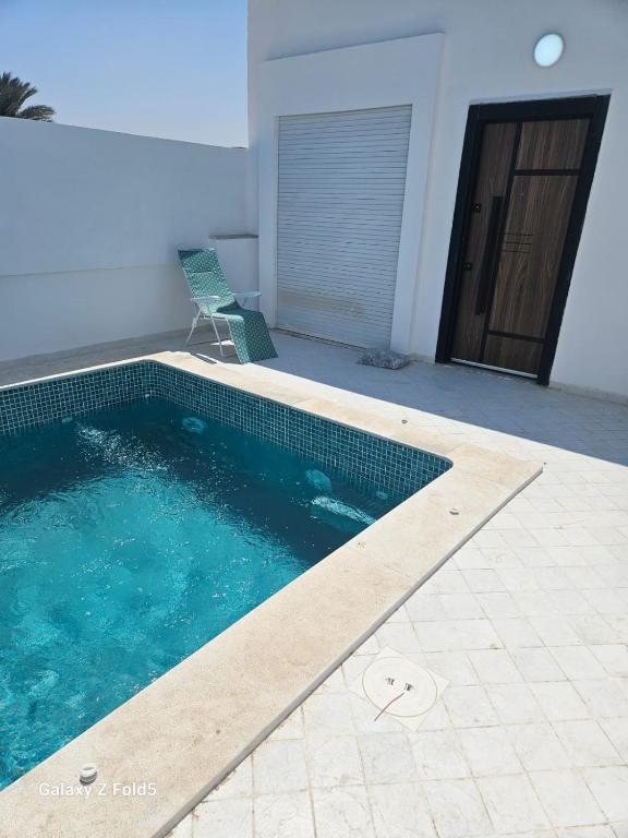 a swimming pool with a chair next to a house at Villa Ayem avec piscine à l'étage in Al Ḩārah al Kabīrah