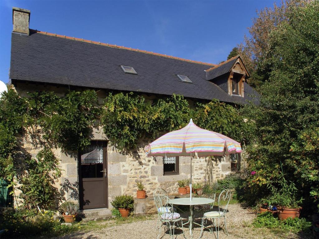 a table with an umbrella in front of a building at Breton Escape in Querrien in Coatviller
