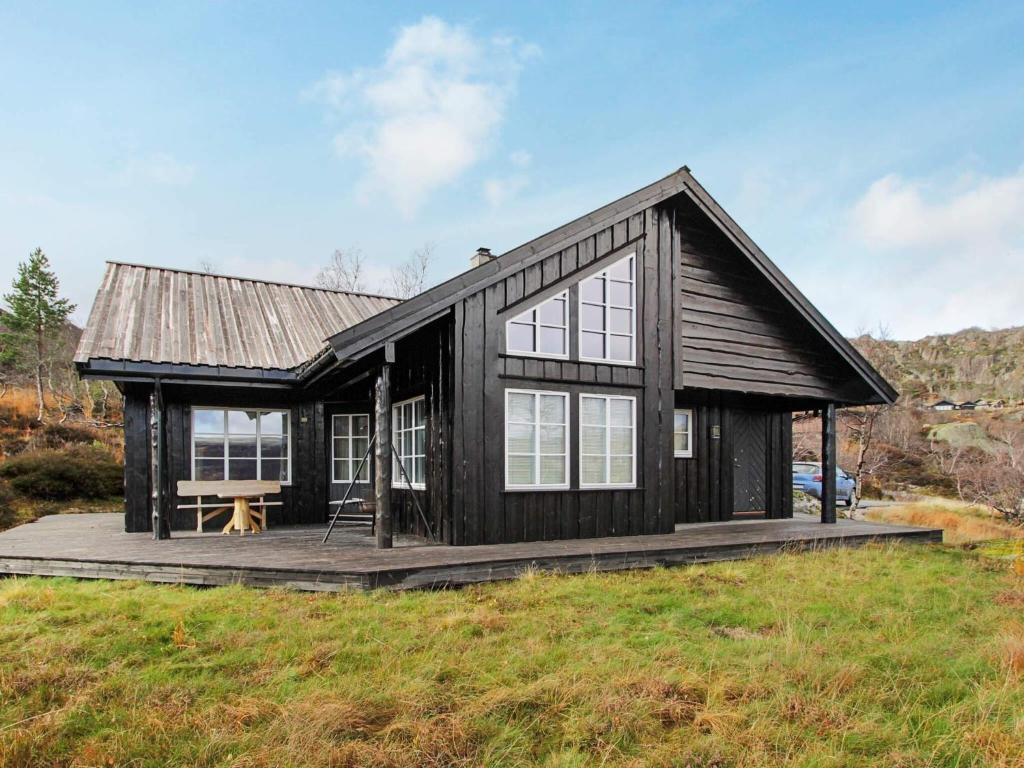 una pequeña casa negra con terraza de madera en 10 person holiday home in ÅSERAL, en Åseral
