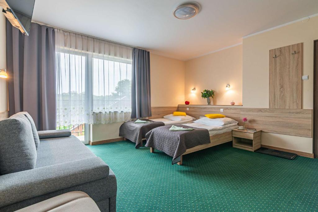 a hotel room with two beds and a couch at Willa Sole in Busko-Zdrój