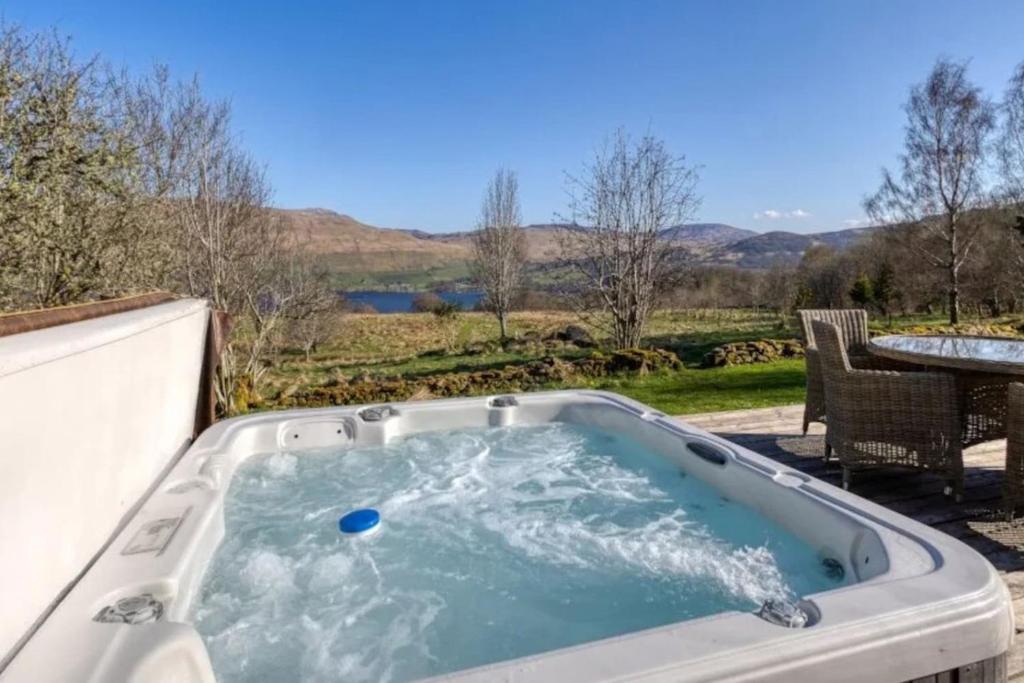 ein Whirlpool auf einer Terrasse mit einem Tisch in der Unterkunft Oak Cottage and Hot Tub, Loch Tay in Lawers