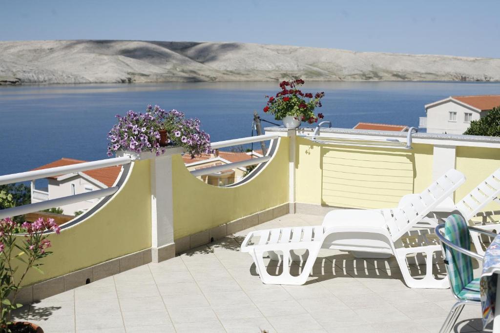 a deck with white chairs and a view of the water at Apartments Roza in Miškovići