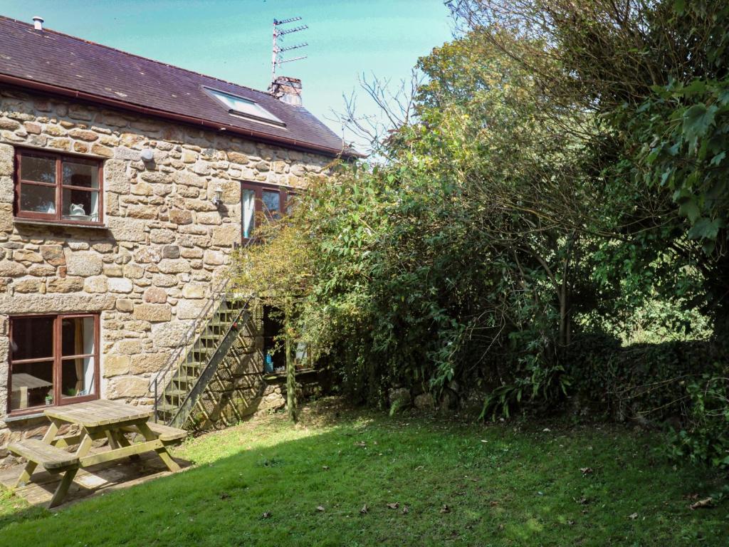 a stone house with a picnic table in front of it at Mill House Barn in Penzance
